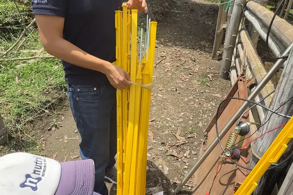 Postes y aisladores del cerco eléctrico instalados en el terreno.