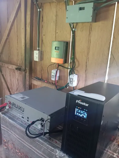 Controlador de carga MPPT, protecciones e inversor instalados en una pared de madera.